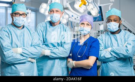 Vielfältiges Team von professionellen Chirurgen, Assistenten und Krankenschwestern stehen stolz mit gekreuzten Armen im Real Modern Hospital mit authentischen Geräten. Stockfoto