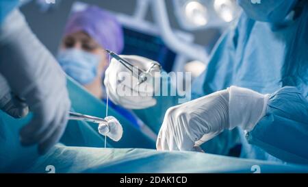 Nahaufnahme der Hände des professionellen Chirurgen Nahtwunde nach erfolgreicher Operation. Im Hintergrund moderner Krankenhaus Operationsraum. Stockfoto