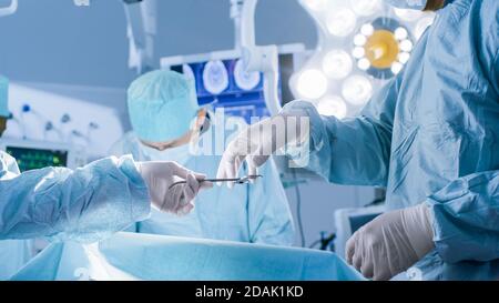 Nahaufnahme im Operationssaal, Assistentin gibt während des Betriebs Instrumente an Chirurgen aus. Operation wird durchgeführt. Professionelle Ärzte Stockfoto