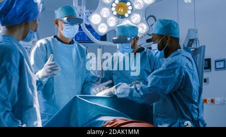 Chirurgen mit Augmented Reality Brillen, die eine moderne Chirurgie im High-Tech-Krankenhaus durchführen. Ärzte und Assistenten, die im Operationssaal arbeiten Stockfoto