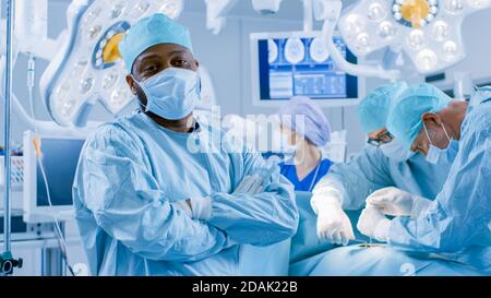 Vielfältiges Team von professionellen Chirurgen, die invasive Chirurgie an einem Patienten im Operationssaal des Krankenhauses durchführen. Chirurgen verwenden und andere Instrumente. Stockfoto