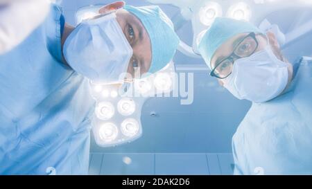Low Angle Shot POV Patientenansicht: Zwei professionelle Chirurgen mit chirurgischen Instrumenten Beginn der Operation. Stockfoto