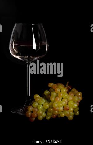 Setting mit frischen Trauben und Wein in Glas schwarz Hintergrund Stockfoto