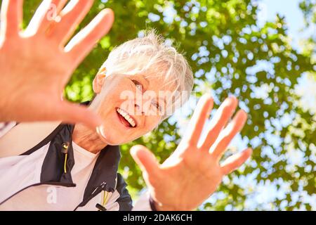 Lachende ältere Frau winkt mit den Händen auf einer Naturwanderung Im Sommer Stockfoto