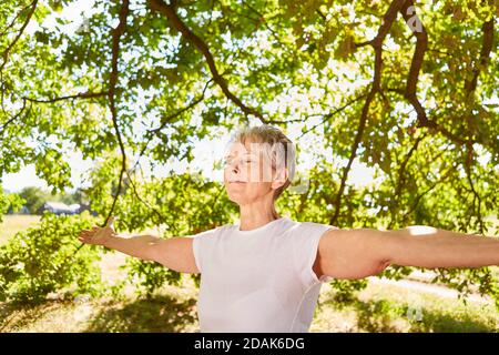 Glückliche ältere Frau mit ausgestreckten Armen eine Meditation und Atemübungen Stockfoto