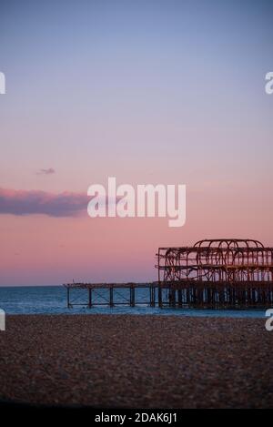 Die ikonischen verbrannten Überreste von Brighton's West Pier an der Brighton Seafront at Dusk im Sommer. Roter Himmel und eine einzige Wolke am Himmel. Brighton Großbritannien Stockfoto