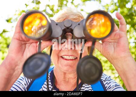Ältere Frau schaut durch das Fernglas als Orientierungskonzept Und Kontrolle Stockfoto