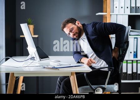 Junger Mann Mit Rückenschmerzen. Falsche Bürohaltung Stockfoto