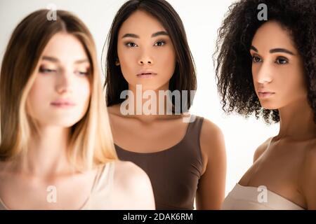 afroamerikanische und asiatische Frauen in der Nähe blonde Modell auf verschwommen Vordergrund auf Weiß isoliert Stockfoto