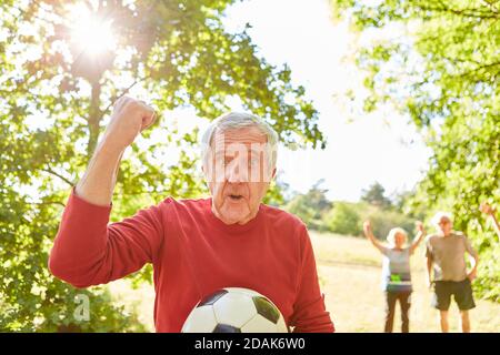 Senior als Rentner mit Fußball jubelt mit geballter Faust Nach einem Fußballspiel Stockfoto