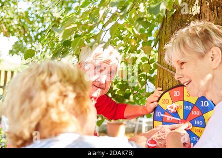 Aktive Senioren spielen Darts und Punkte im Garten Im Sommer Stockfoto