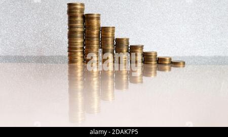 Stapel von Münzen auf silbernem Hintergrund mit Spiegelung in Glas. Platz für Text kopieren. Stockfoto