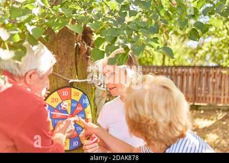 Senioren spielen Darts zusammen am Ton Ziel in der Garten im Sommer Stockfoto