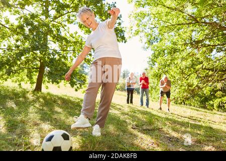 Aktive und vitale Senioren spielen Fußball auf einer Wiese Im Park mit Freunden Stockfoto