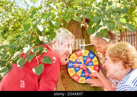 Drei Senioren, die Darts an der Wurfscheibe spielen, zählen Punkte im Wettbewerb Stockfoto