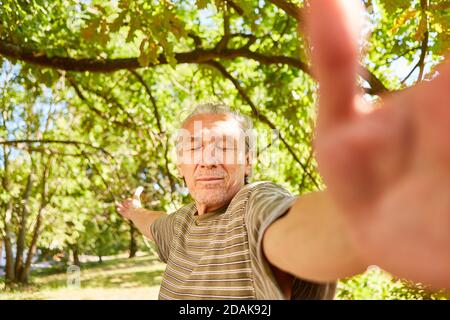 Senior mit geschlossenen Augen macht eine Qi Gong Atemübung Im Sommer in der Natur Stockfoto