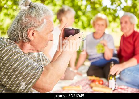 Älterer Mann, der ein Selfie seiner Freunde beim Picknick gemacht hat Mit Smartphone Stockfoto