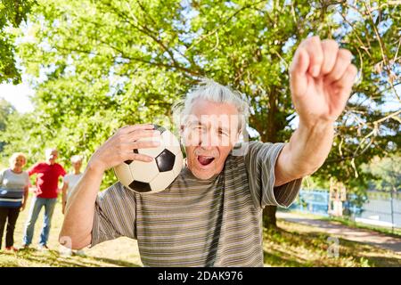 Senior Mann mit Fußball ist glücklich als Sieger und Cheers mit geballter Faust Stockfoto