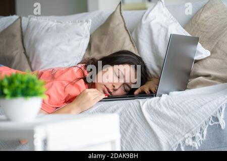 Das Mädchen schlief während der Arbeit auf einem Laptop ein. Schlaf während der Arbeitszeit. Probleme mit Freiberuflern. Stockfoto