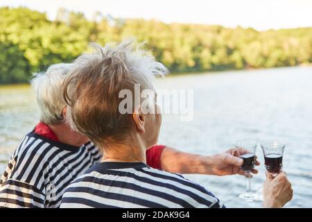 Ein älteres Paar trinkt zusammen ein Glas Rotwein Entspannen am Seeufer Stockfoto