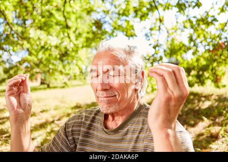 Entspannte Senior mit geschlossenen Augen tun eine Atemübung als Zen-Meditation Stockfoto