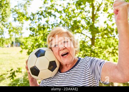 Vital ältere Frau mit Fußball jubelt mit geballten Fäusten Nach dem Spiel im Park im Sommer Stockfoto