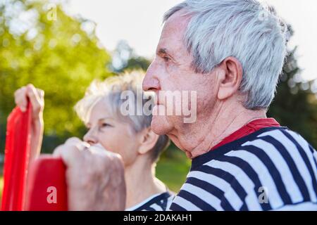Ein paar Senioren mit Rudern von Ruderboot schaut hinein Die Entfernung im Sommer am See Stockfoto