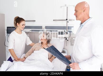 Medizinische Betreuung von Senioren. Älterer Patient, der in einem Krankenhausbett liegt und eine Schwesternunterstützung hat. Klinische Behandlung und Altenpflege Stockfoto