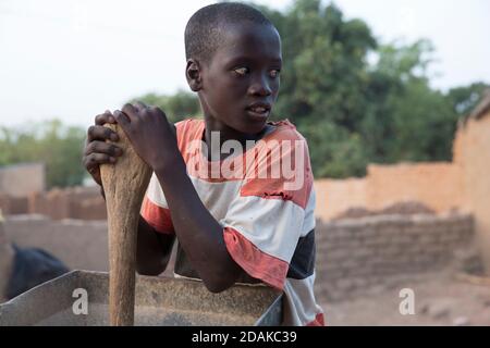 Selingue, Mali, 27. April 2015; Reissentälung. Adama Tankara, 12, arbeitet mit seinem Bruder zusammen. Die Maschine gehört ihnen. Stockfoto