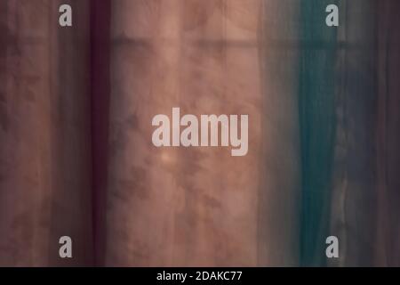 Transparente Vorhänge in rot und türkis geben einen Blick auf Blätter auf einem Baum Stockfoto