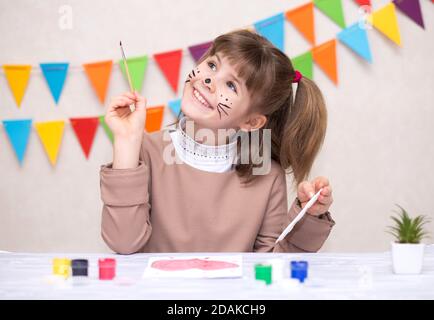 Kinder machen hausgemachte Grußkarte. Kleines Mädchen malt Herz auf hausgemachte Grußkarte als Geschenk für den Muttertag. Traditionelles Spielkonzept. Kunst und cra Stockfoto