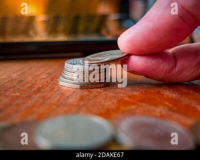 Hand legen Münzen zu Stapel von Münzen. Ein Haufen Münzen im Vordergrund. Stockfoto