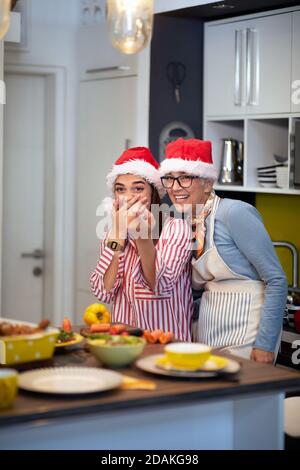 Mutter und Tochter posieren für ein Foto in der Küche in festlicher Atmosphäre an Weihnachten. Weihnachten, Familie, zusammen Stockfoto