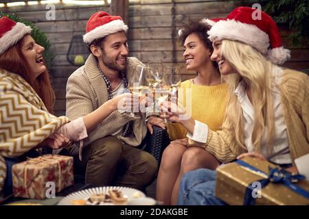 Gruppe von multiethnischen Freunden Toasting mit Sekt und santa Klausel Hüte auf Köpfen. Weihnachtszeit, Neujahr Konzept Stockfoto