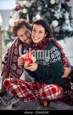 Fröhliches Paar teilt Geschenke an Weihnachten Morgen zu Hause; White Christmas Konzept Stockfoto