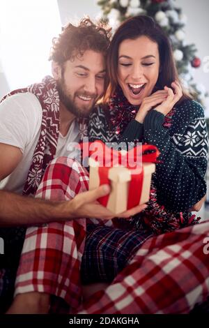 Liebevolles Paar teilt Geschenke am Weihnachtsmorgen zu Hause Stockfoto