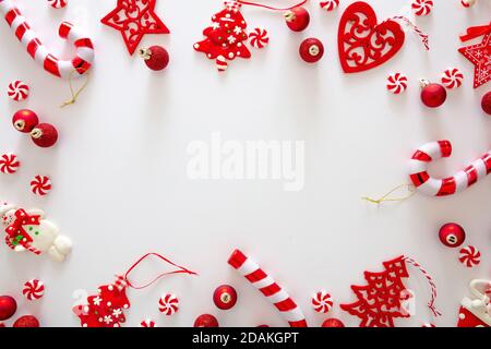 Weihnachtsschmuck Kugeln und süße Bonbons rote Farbe vor weißem Hintergrund, Weihnachtsrahmen flach legen, Urlaub Grußkarte Vorlage, Draufsicht Stockfoto