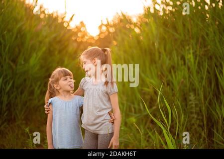 Zwei Mädchen Schwestern Spaß zusammen im Park, zeigen Zunge zu einander. Aktivitäten im Freien. Stockfoto