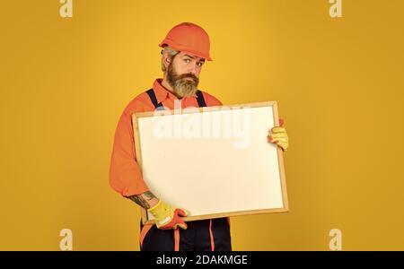 Mann in harter Mütze. Builder zeigt auf Flipchart. Architekt Arbeiter halten Flipchart. Präsentieren Flipchart bei der Sitzung. Männliche Bauarbeiter. Copy Raum. Planung neuer Projekt. Serious Mann Präsentation. Stockfoto