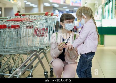 Mama und Kind tragen Schutzmasken tragen Desinfektionsmittel Gel in Ein Einkaufszentrum Stockfoto