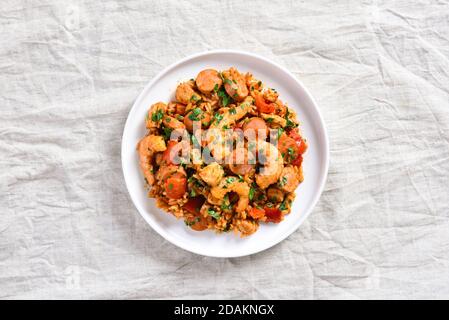 Kreolische Jambalaya mit Huhn, geräucherten Würstchen und Gemüse auf dem Teller auf hellem Hintergrund. Draufsicht, flach liegend, Nahaufnahme Stockfoto