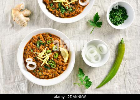 Keema Curry in Schüssel über hellem Hintergrund. Indische und pakistanische Gerichte. Draufsicht, flach liegend Stockfoto