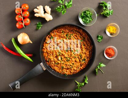 Keema Curry in Bratpfanne über dunklem Hintergrund. Indische und pakistanische Gerichte. Draufsicht, flach liegend, Nahaufnahme Stockfoto