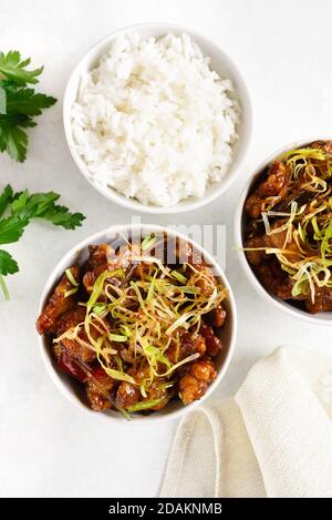 Würziges, im Knoblauch gebratenes Huhn (Kkanpunggi). Asiatisches Huhn in süß-saurer Sauce in Schüssel auf weißem Hintergrund. Draufsicht, flaches Lay Stockfoto