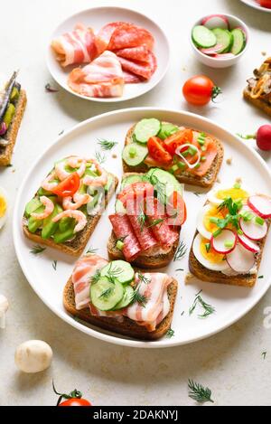 Sortiment offene Sandwiches auf Teller über hellem Stein Hintergrund. Leckerer Snack. Stockfoto