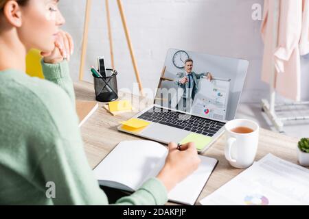 Geschäftsmann zeigt mit dem Finger in die Nähe des Flipchart auf dem Bildschirm des Laptops Fast freiberuflicher Text auf Notebook während des Webinars über verschwommene Vordergrund Stockfoto