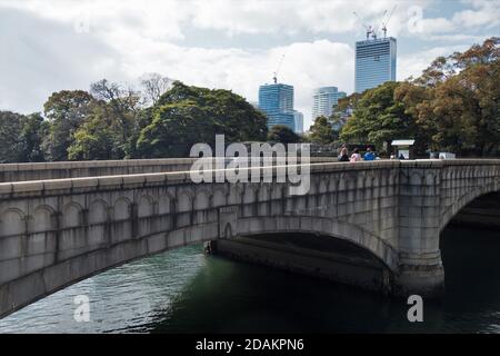 Menschen, die über eine Fußgängerbrücke in die Hamarikyu-Gärten in Tokio, Japan, gehen. Stockfoto