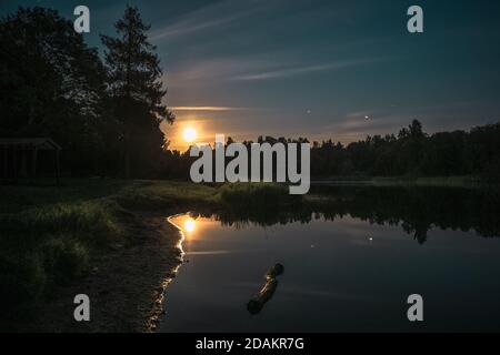 Nachtlandschaft mit der Spiegelung des Mondes im See. Stockfoto