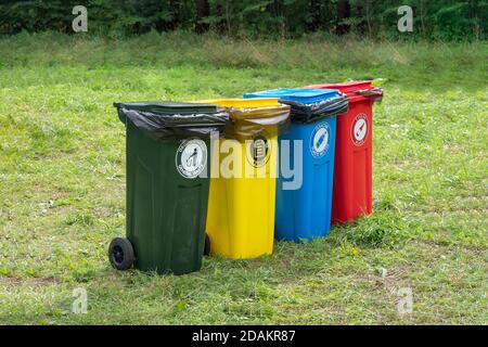 Farbige Behälter für getrennte Müllabfuhr im grünen Rasen. Stockfoto