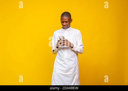 Junger afrikanischer muslimischer Mann, der sein Telefon benutzt Stockfoto